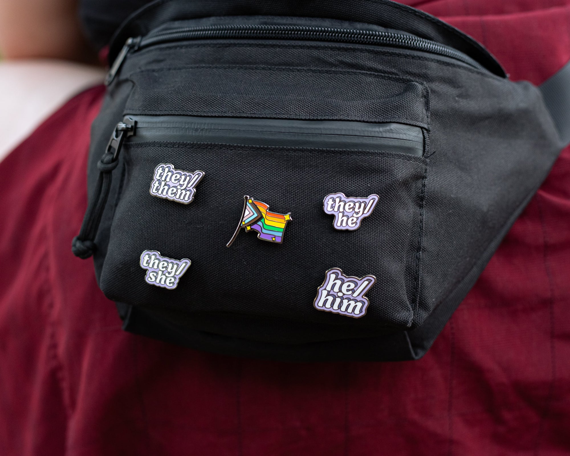 Pronoun Enamel Pins on a Black Fanny Pack