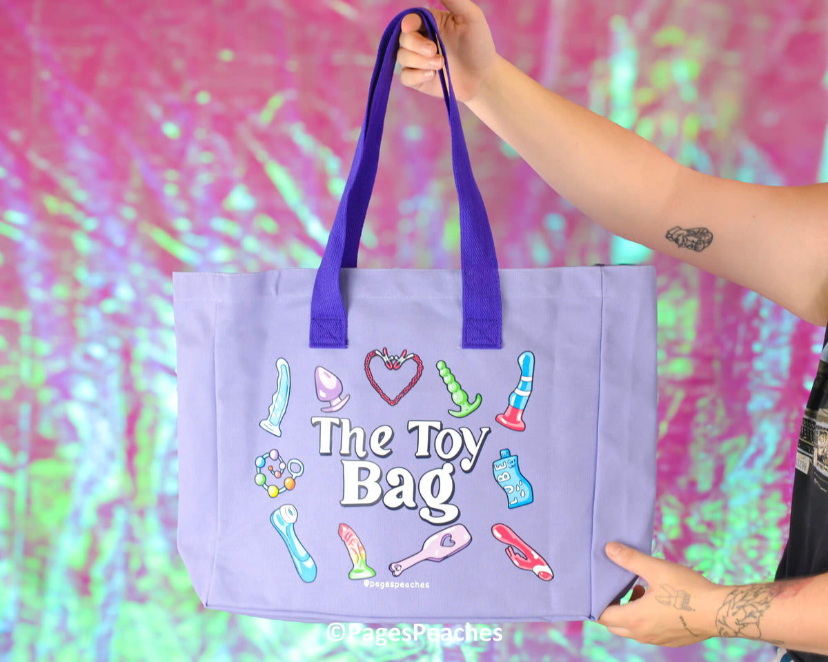 Purple tote bag with colorful illustrations and &#39;The Toy Bag&#39; text, held against a vibrant, multicolored background.