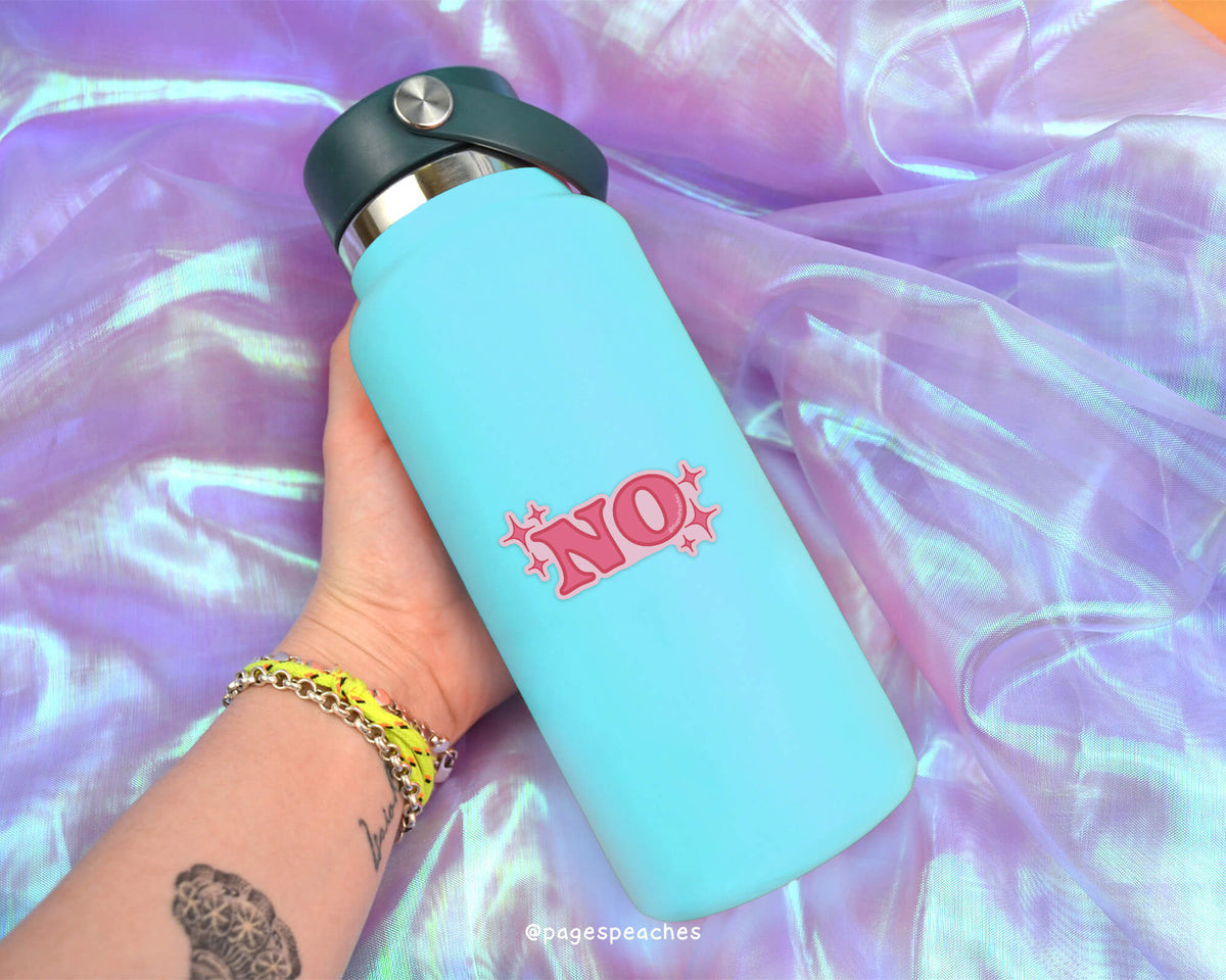 A person&#39;s hand holding a blue water bottle with a pink &quot;NO&quot; sticker on it, against a purple fabric background.