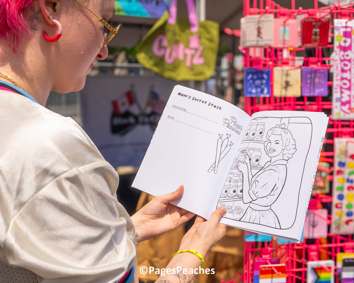 A person is holding a coloring book with a page titled &quot;Mom&#39;s Secret stash&quot; and an illustration of a woman. The person is looking at the book, which is placed on a table.