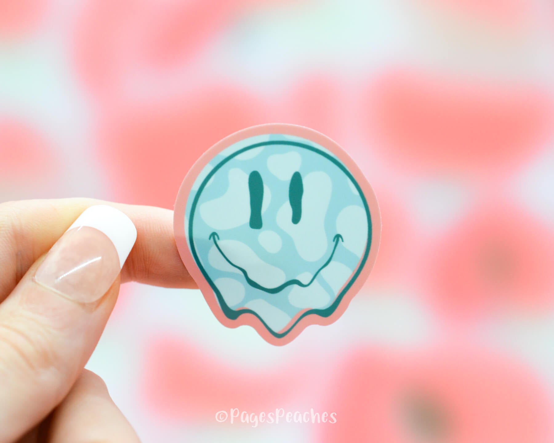 Sticker of a blue melting smiley face with cow print on a pink background