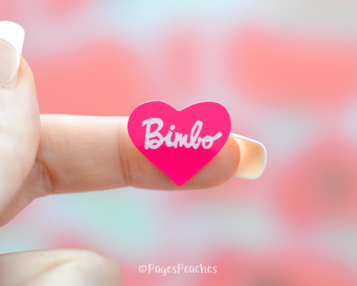 Small Pink Heart Sticker that says bimbo stuck to a finger