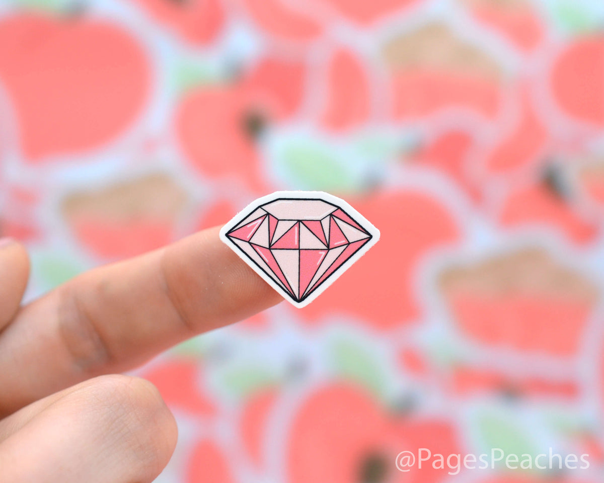 Small Sticker of a pink diamond stuck to a finger