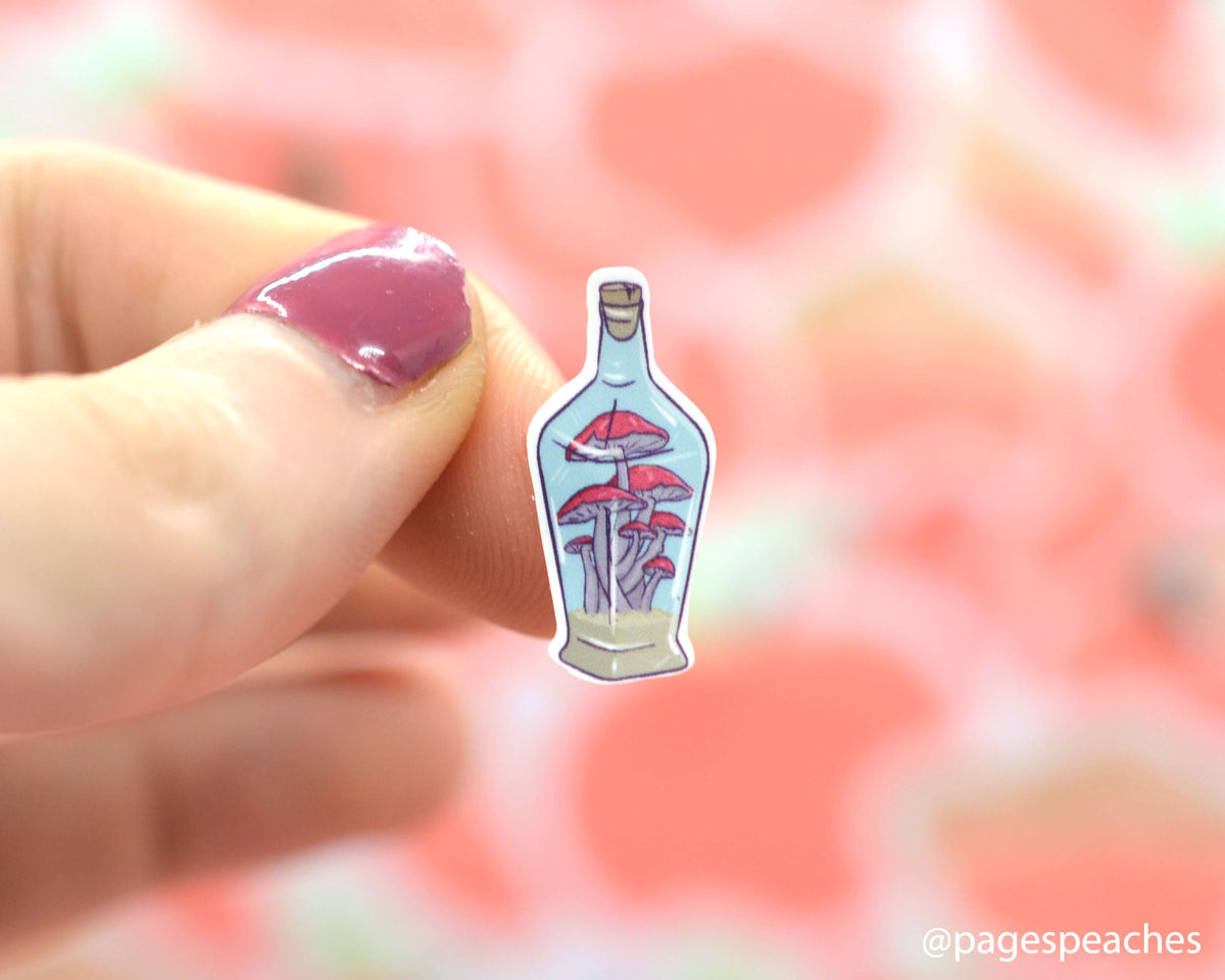 Small Sticker of mushrooms in a jar that is stuck to a finger