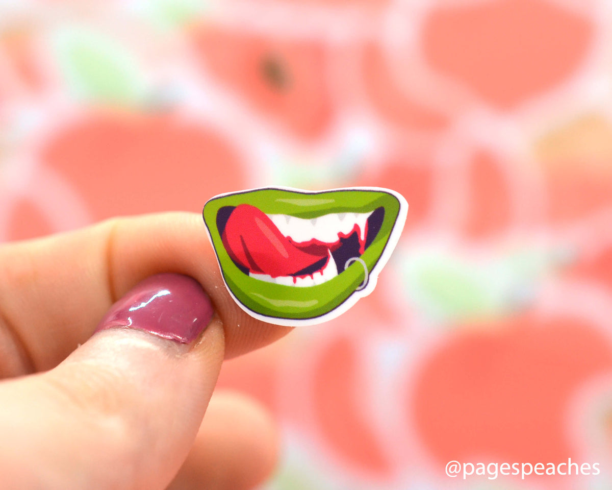 Small Sticker of a vampire licking its lips stuck to a finger