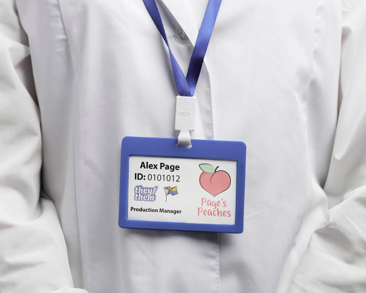 Name Badge with a They/Them pronoun sticker and progress pride flag sticker
