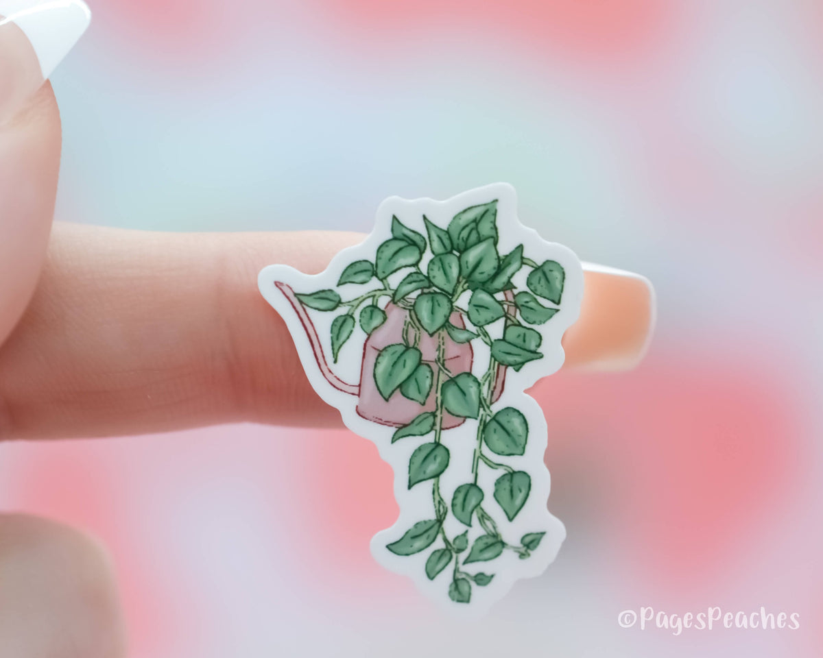 Small Sticker of a pothos plant in a watering can stuck to a finger