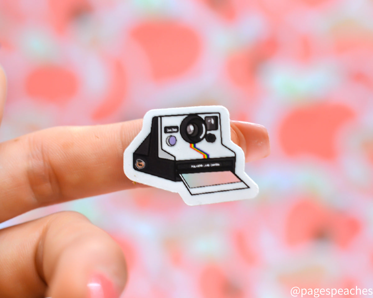 Small Sticker of a retro instant camera stuck to a finger