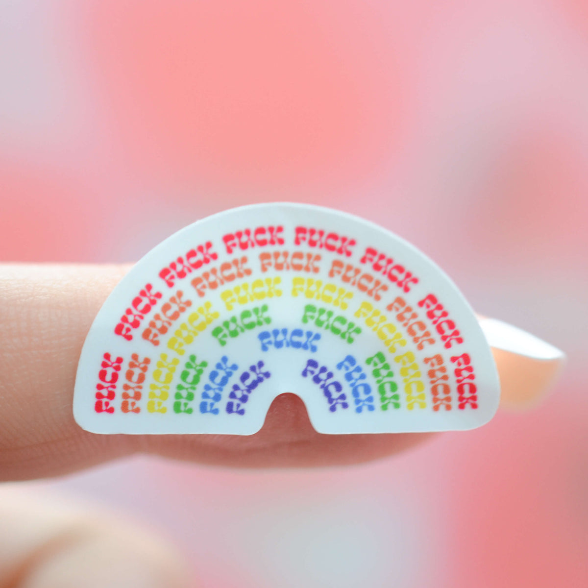 Small Sticker of a rainbow that says fuck stuck to a finger