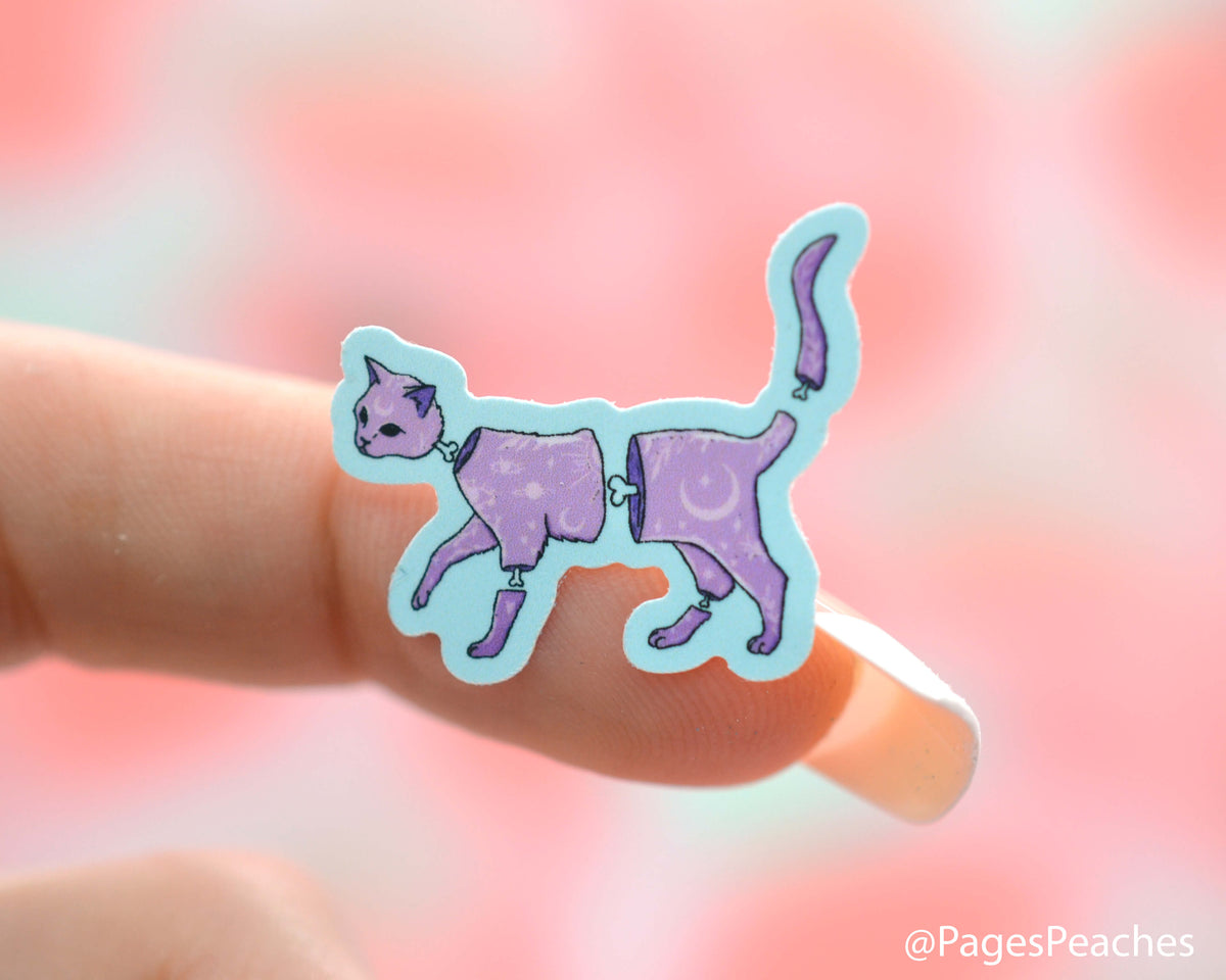 Small sticker of a purple cat that is stuck to a finger