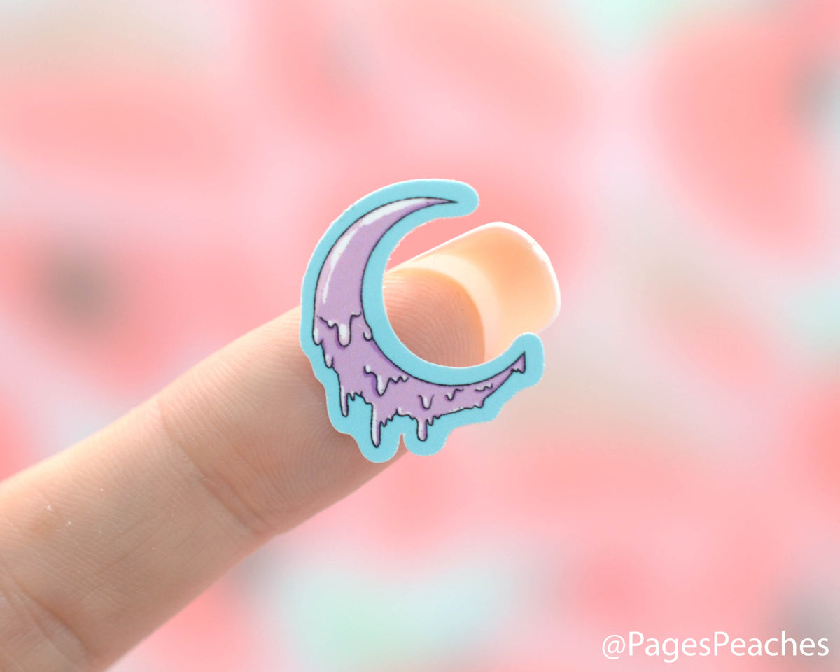 Small Sticker of a purple melting moon stuck to a finger