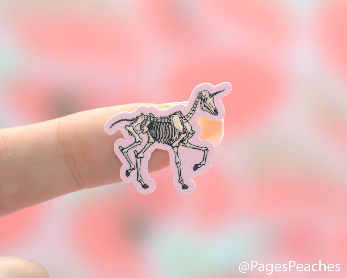 Small unicorn skeleton sticker stuck to a finger